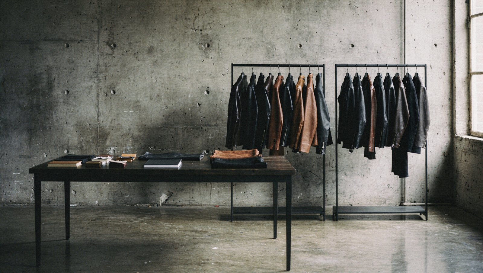 Showroom mit Lederjacken an Kleiderstangen und einem Mustertisch